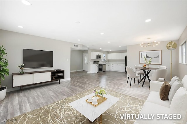 living area featuring light wood-style flooring, a chandelier, baseboards, and recessed lighting