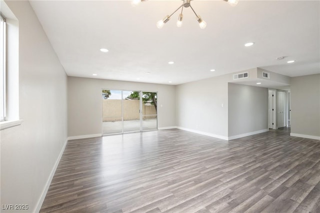 empty room with a chandelier, wood finished floors, baseboards, and recessed lighting