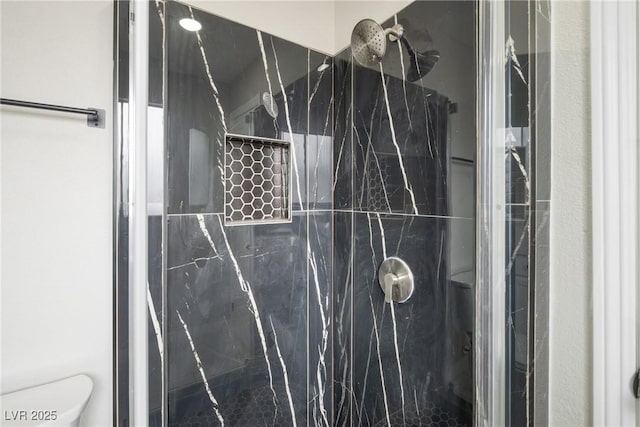 bathroom with a marble finish shower and toilet