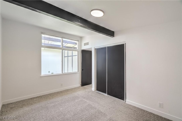 unfurnished bedroom with beam ceiling, baseboards, carpet flooring, and a closet