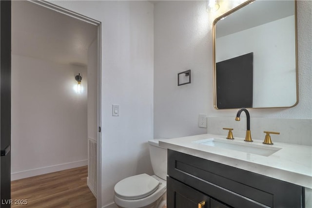 bathroom featuring wood finished floors, toilet, vanity, and baseboards