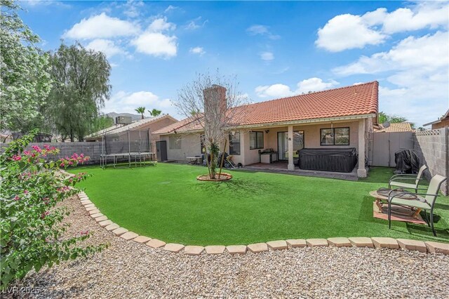 5884 Deer Valley Dr, Las Vegas, NV 89156 - rear view of house with a trampoline, a hot tub, a tile roof, stucco siding, and a patio
