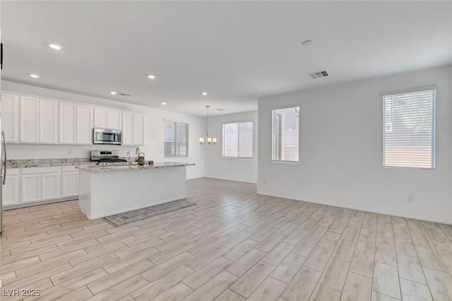 10735 Galveston Bay St, Las Vegas, NV 89179 - kitchen with stainless steel appliances, open floor plan, light wood-style flooring, light stone counters, and recessed lighting