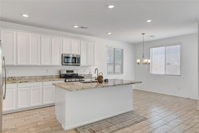 10735 Galveston Bay St, Las Vegas, NV 89179 - kitchen featuring appliances with stainless steel finishes, a sink, wood finish floors, a chandelier, and white cabinetry