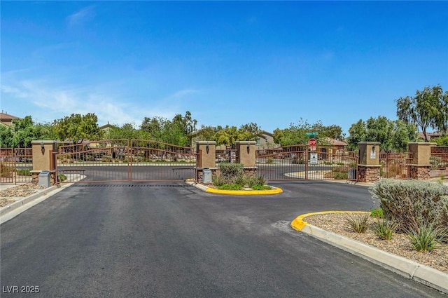 10735 Galveston Bay St, Las Vegas, NV 89179 - view of asphalt road featuring a gate, curbs, a gated entry, and traffic signs