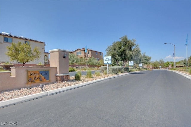 10735 Galveston Bay St, Las Vegas, NV 89179 - view of asphalt street featuring street lights, curbs, and a gated entry