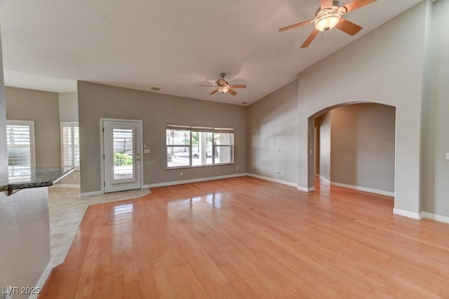 7540 Crystal Cave Dr, Las Vegas, NV 89117 - unfurnished living room featuring ceiling fan, arched walkways, light wood-style floors, and vaulted ceiling