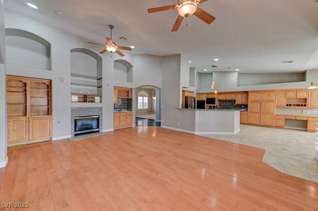 7540 Crystal Cave Dr, Las Vegas, NV 89117 - unfurnished living room with a ceiling fan, recessed lighting, a fireplace with flush hearth, built in shelves, and arched walkways
