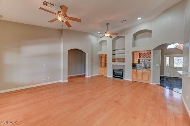 7540 Crystal Cave Dr, Las Vegas, NV 89117 - unfurnished living room featuring arched walkways, a ceiling fan, a tiled fireplace, light wood-style floors, and recessed lighting