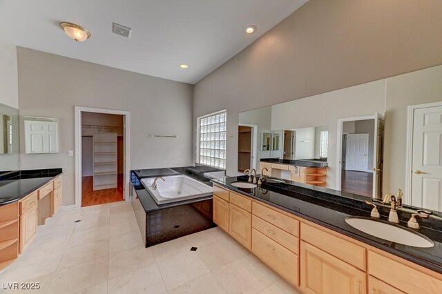 7540 Crystal Cave Dr, Las Vegas, NV 89117 - bathroom featuring double vanity, a garden tub, vaulted ceiling, tile patterned floors, and a walk in closet