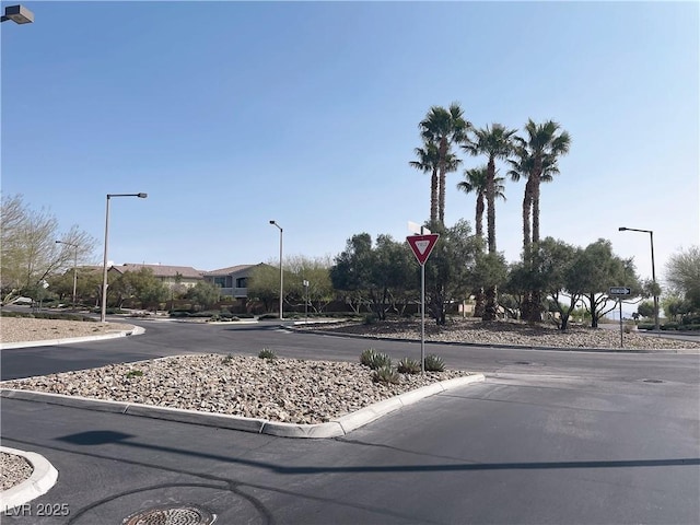 view of asphalt street with curbs, street lights, and traffic signs