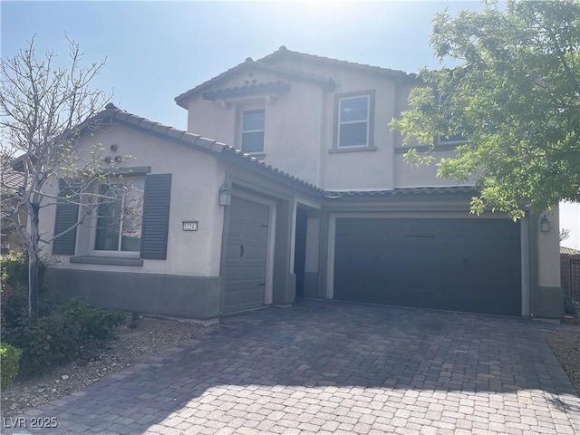 view of front of home with decorative driveway, stucco siding, a garage, and a tiled roof