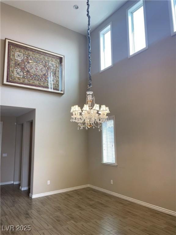 detailed view of a chandelier, baseboards, and wood finished floors