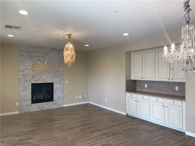 kitchen with dark wood-style floors, a chandelier, baseboards, a fireplace, and pendant lighting