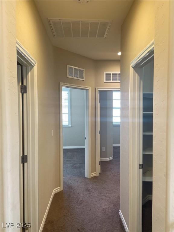 corridor with dark colored carpet and baseboards