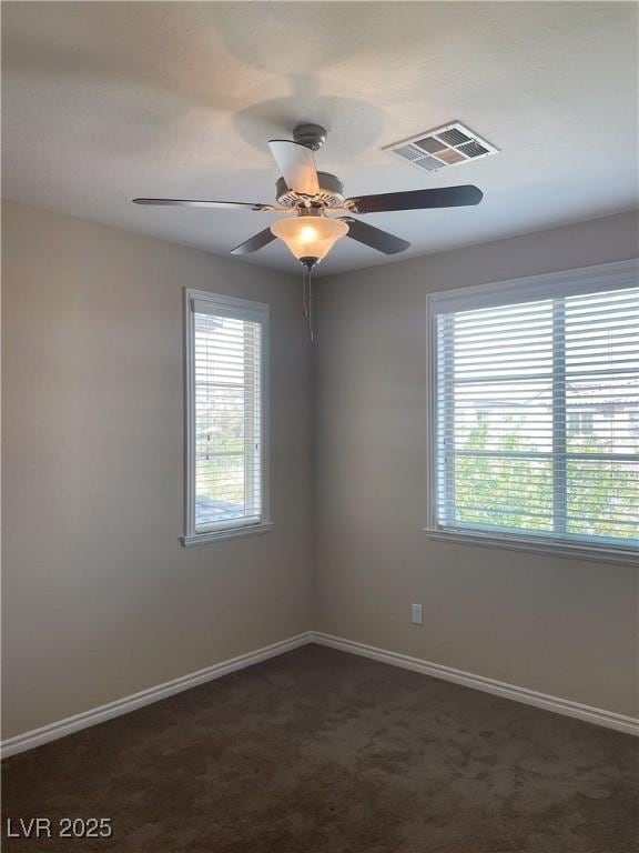 unfurnished room featuring baseboards, dark carpet, and ceiling fan