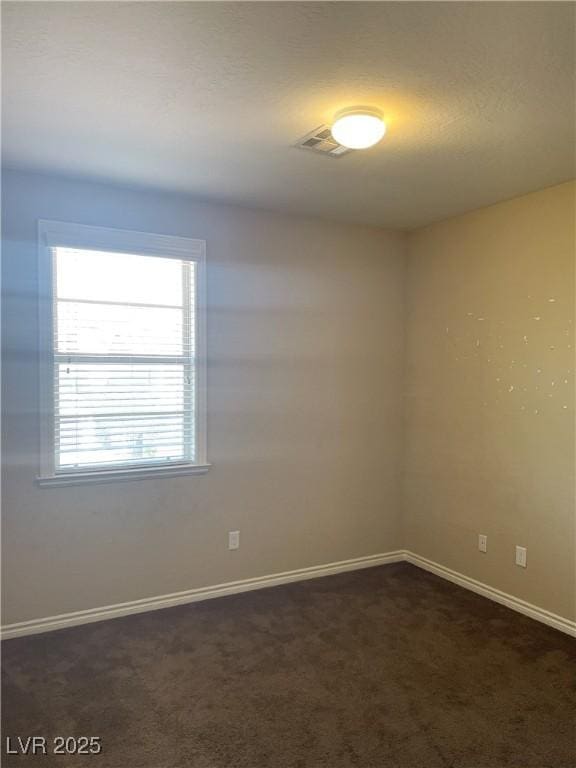 unfurnished room featuring dark carpet and baseboards