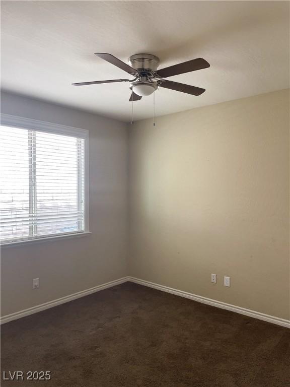 unfurnished room featuring ceiling fan, dark carpet, and baseboards