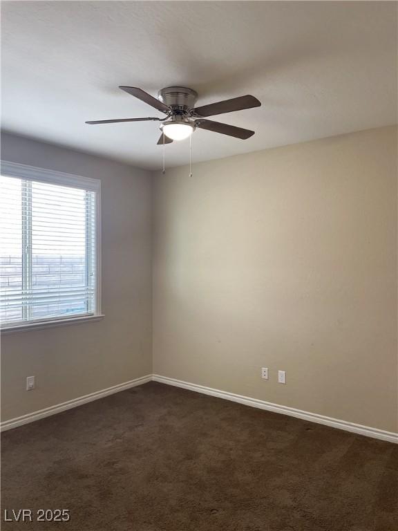 unfurnished room featuring dark colored carpet, a ceiling fan, and baseboards