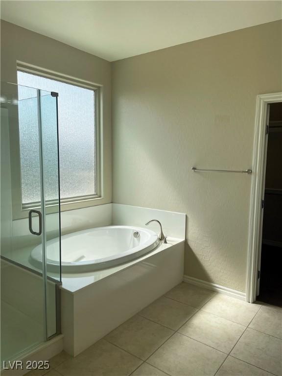 full bathroom with a bath, a stall shower, baseboards, and tile patterned flooring