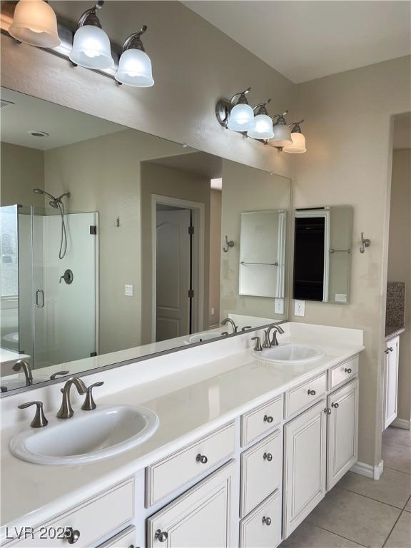 bathroom with a stall shower, tile patterned floors, double vanity, and baseboards