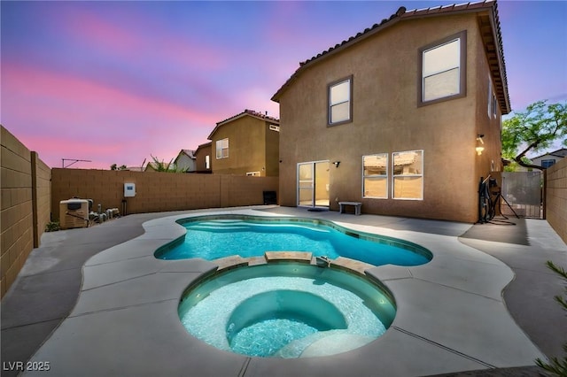 view of pool featuring a pool with connected hot tub, a patio, and a fenced backyard