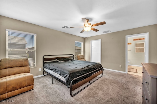 bedroom featuring light colored carpet, baseboards, ceiling fan, and ensuite bath