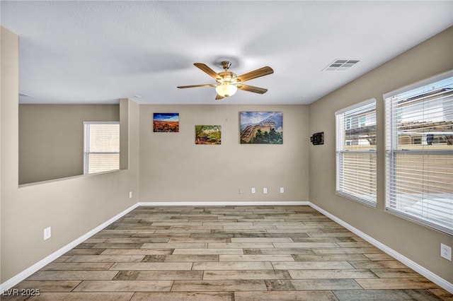 spare room with wood finished floors, a ceiling fan, and baseboards