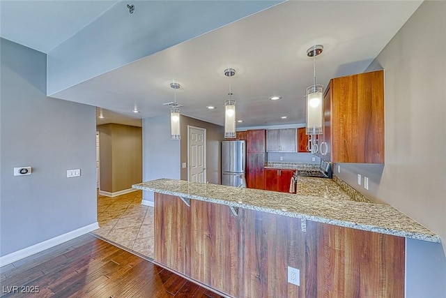150 Las Vegas Blvd Unit 2016, North Las Vegas, NV 89101 - kitchen featuring freestanding refrigerator, a peninsula, baseboards, light wood-style floors, and light stone counters