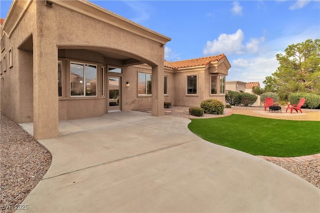 10801 Clarion Ln, Las Vegas, NV 89134 - rear view of house with a fire pit, stucco siding, a patio, a lawn, and a tiled roof