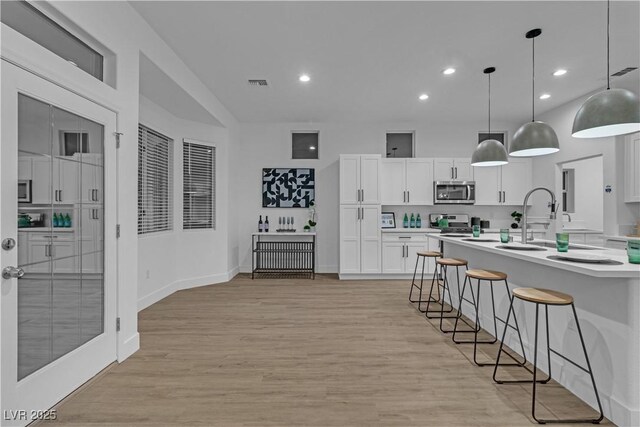 10801 Clarion Ln, Las Vegas, NV 89134 - kitchen featuring a breakfast bar, light countertops, white cabinetry, light wood finished floors, and recessed lighting