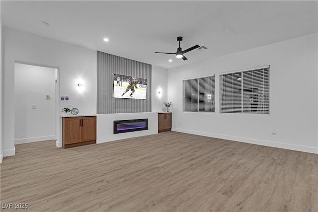 10801 Clarion Ln, Las Vegas, NV 89134 - unfurnished living room featuring light wood-style flooring, a ceiling fan, a glass covered fireplace, recessed lighting, and baseboards