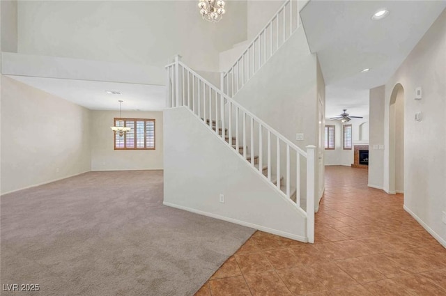 11444 Steponia Bay St, Las Vegas, NV 89141 - stairway with a chandelier, tile patterned floors, a fireplace with raised hearth, ceiling fan, and baseboards