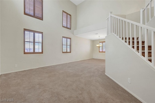 11444 Steponia Bay St, Las Vegas, NV 89141 - unfurnished living room featuring a chandelier, a high ceiling, carpet floors, stairway, and baseboards