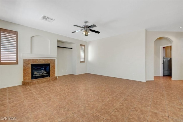 11444 Steponia Bay St, Las Vegas, NV 89141 - unfurnished living room featuring a ceiling fan, arched walkways, a tiled fireplace, and baseboards