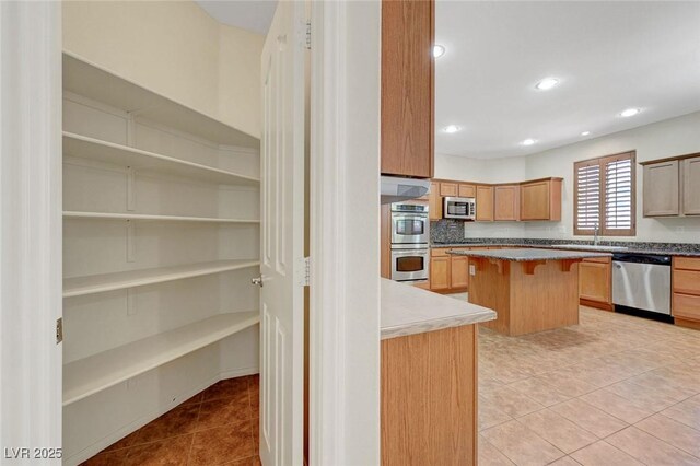 11444 Steponia Bay St, Las Vegas, NV 89141 - kitchen featuring appliances with stainless steel finishes, a breakfast bar, light tile patterned floors, a sink, and recessed lighting