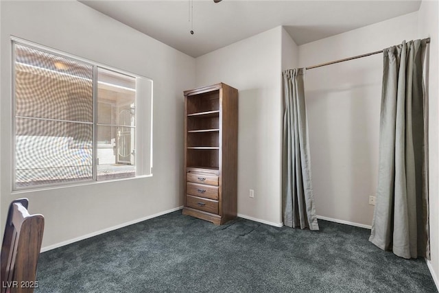 unfurnished bedroom featuring dark colored carpet and baseboards