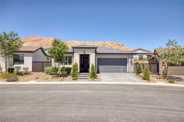 25 Red Creek Bluff St, Henderson, NV 89011 - ranch-style house with an attached garage, driveway, a mountain view, a gate, and stucco siding