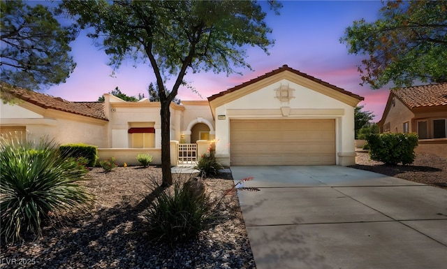 mediterranean / spanish-style home featuring driveway, stucco siding, an attached garage, and a tile roof