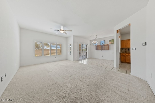 unfurnished living room featuring ceiling fan, light colored carpet, and light tile patterned floors
