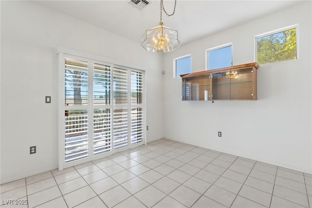 unfurnished room featuring a chandelier, healthy amount of natural light, and light tile patterned floors