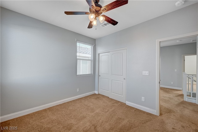 unfurnished bedroom with carpet flooring, a closet, baseboards, and a ceiling fan