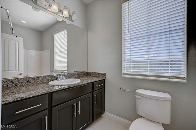 bathroom featuring plenty of natural light, toilet, vanity, and baseboards