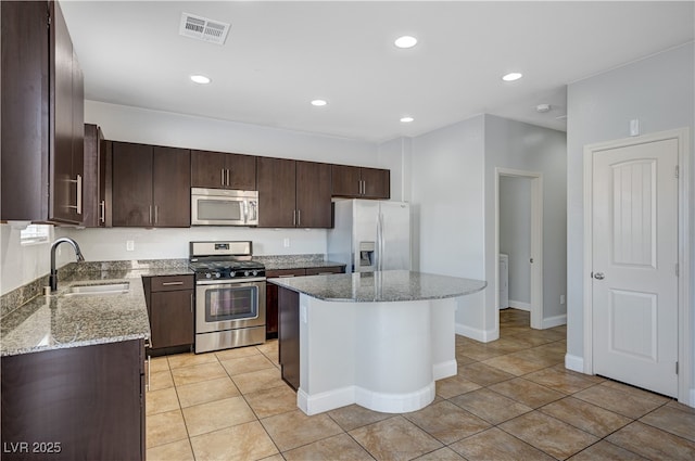 kitchen with stainless steel appliances, a sink, dark brown cabinetry, a center island, and recessed lighting