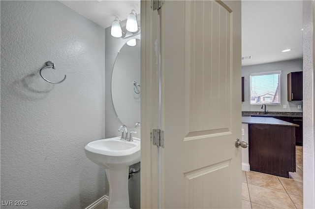 bathroom with tile patterned flooring, a textured wall, and a sink