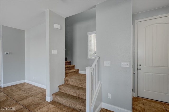 tiled entrance foyer featuring stairs and baseboards
