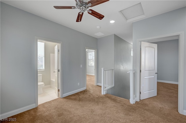 unfurnished bedroom with carpet, attic access, baseboards, and ensuite bath