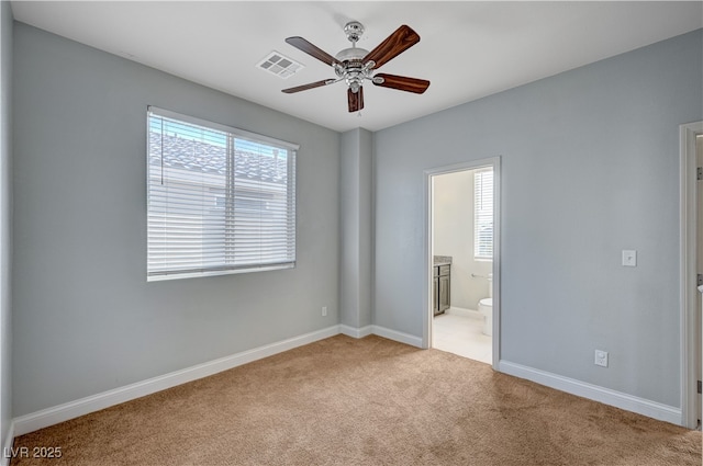 unfurnished bedroom featuring light carpet, baseboards, connected bathroom, and a ceiling fan