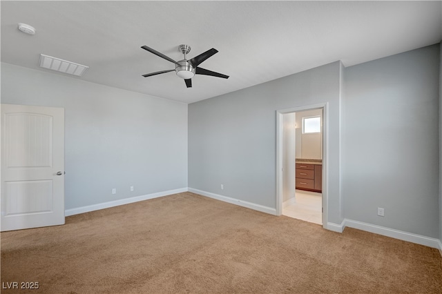 unfurnished bedroom featuring light colored carpet, baseboards, ensuite bath, and ceiling fan
