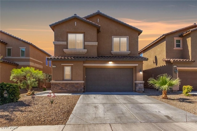view of front of home featuring stone siding, a tile roof, a garage, and stucco siding
